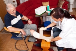 caregiver dressing an elderly man's wound